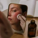 Rougeur visage : compresse tiède sur joue irritée sur un miroir